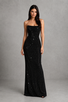 Woman wearing a black strapless gown with sequins on a gray background