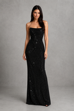 Woman wearing a black strapless gown with sequins on a gray background
