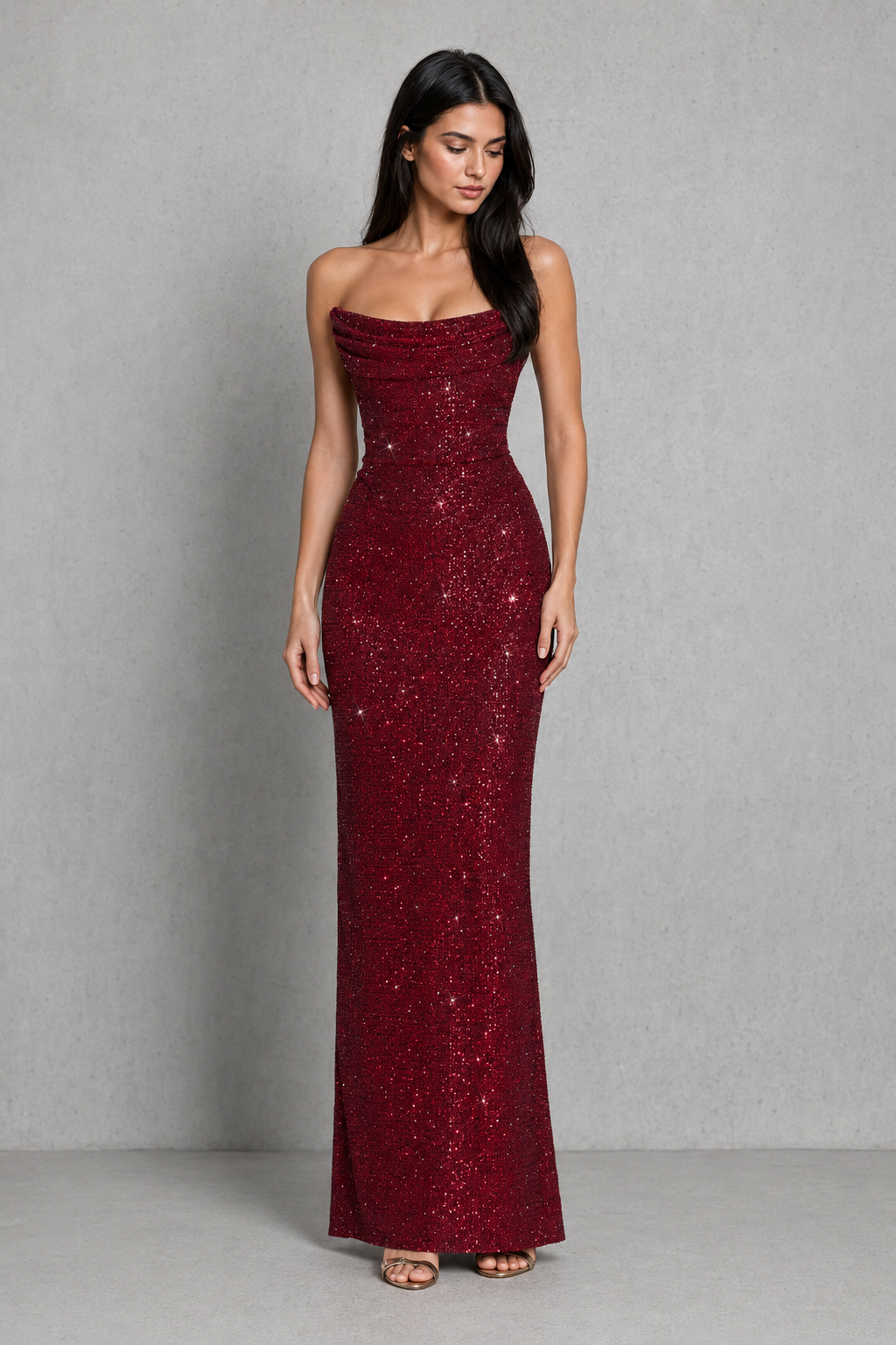Woman wearing a burgundy strapless sequin gown against a gray background