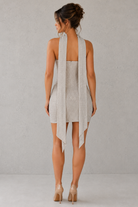 Woman wearing a light-colored dress with a plain background