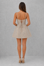 Woman wearing a beige lace-up dress against a gray background