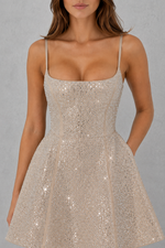 Woman wearing a sparkly silver dress against a gray background