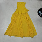 Yellow dress with ruffled layers on a light gray surface