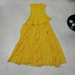 Yellow dress with ruffled layers on a light gray surface