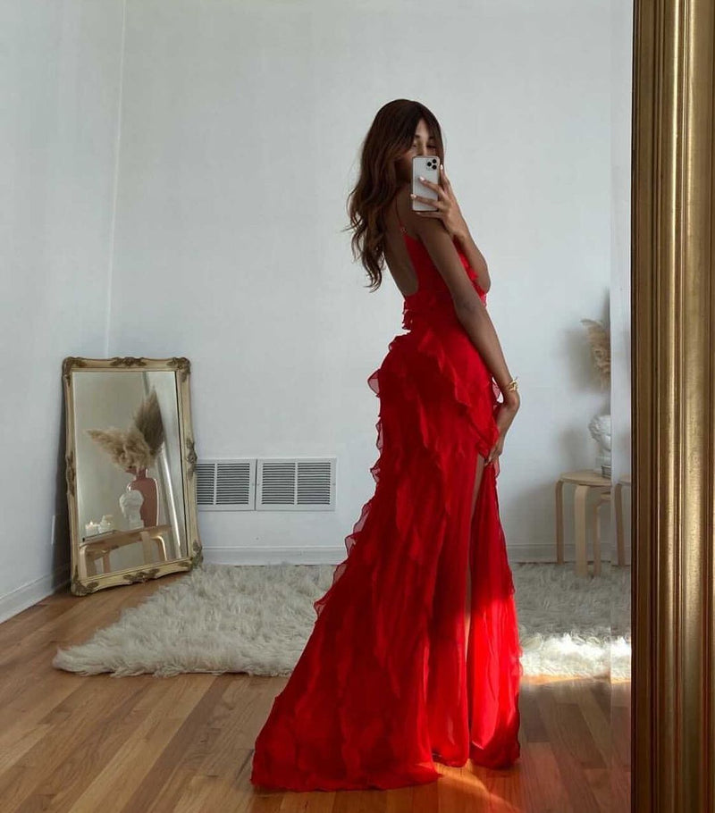 Woman in a red dress taking a mirror selfie in a room with a rug and framed picture on the wall.