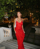 Woman in a red dress standing outdoors with trees and lanterns in the background