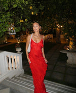 Woman in a red dress standing outdoors with trees and lanterns in the background