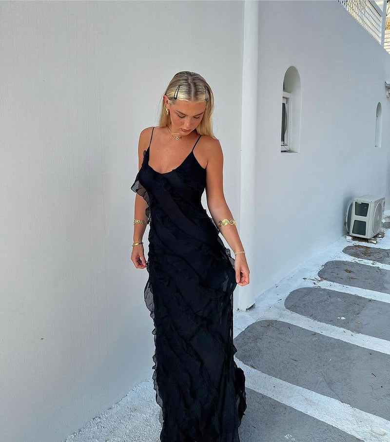 Woman in a black evening gown standing on a white pathway.