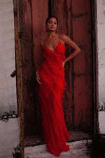 Woman in a red dress standing in front of a rustic wooden door.
