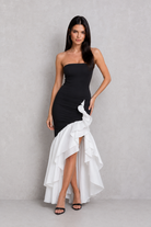 Woman wearing a black and white dress against a plain background