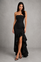 Woman wearing a black strapless dress with ruffled layers against a gray background