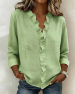 Green blouse with ruffled details worn by a person against a neutral background