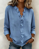Woman wearing a blue blouse with ruffled details on a plain background