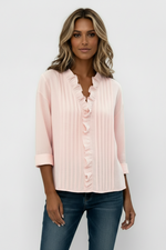 Person wearing a light pink blouse with ruffled details on a plain background