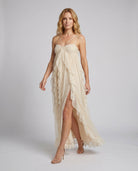 Woman wearing a beige dress with thin straps on a plain background