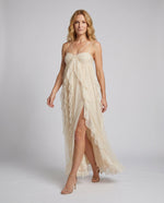 Woman wearing a beige dress with thin straps on a plain background