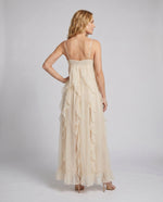 Woman wearing a beige evening gown against a plain background