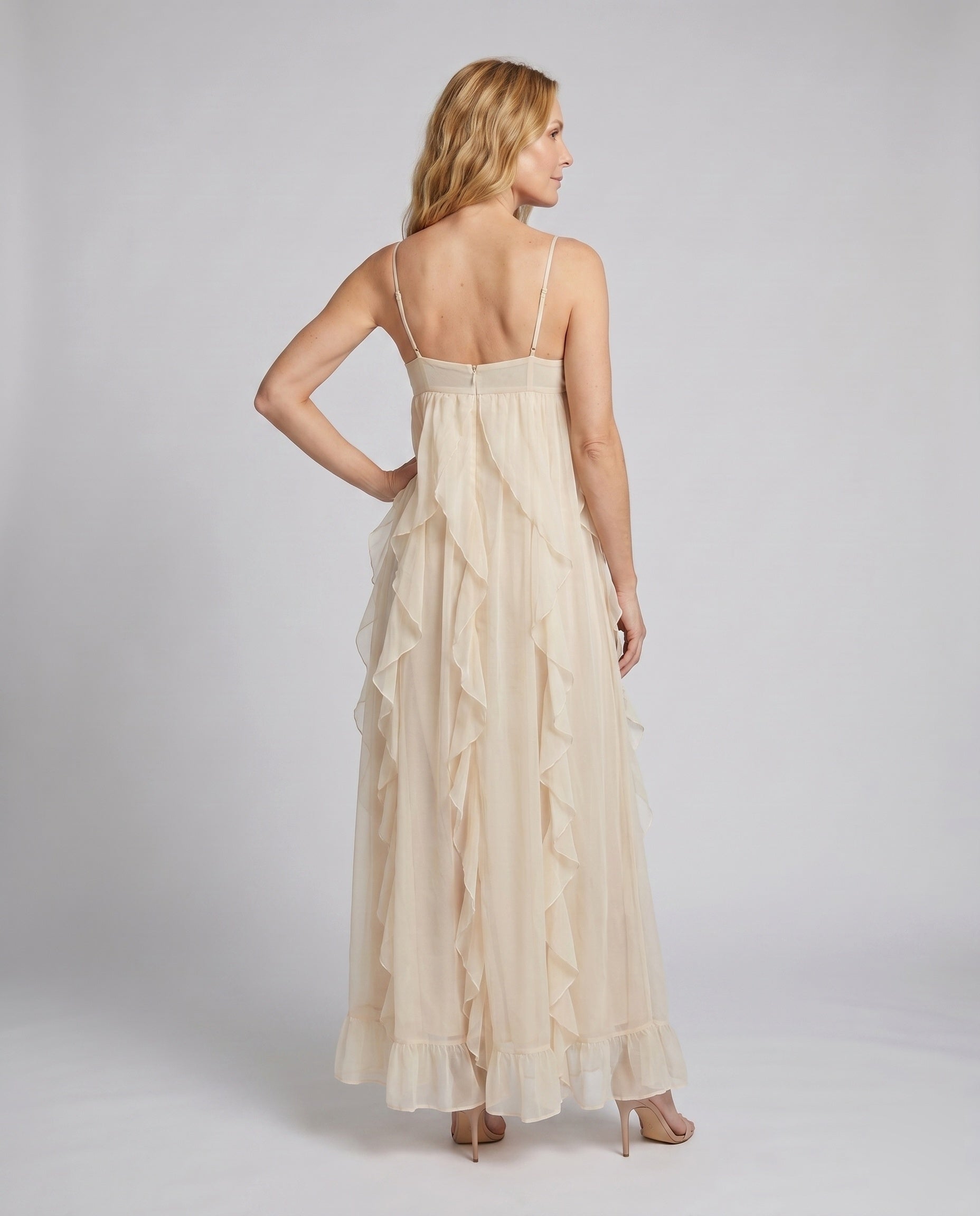 Woman wearing a beige evening gown against a plain background