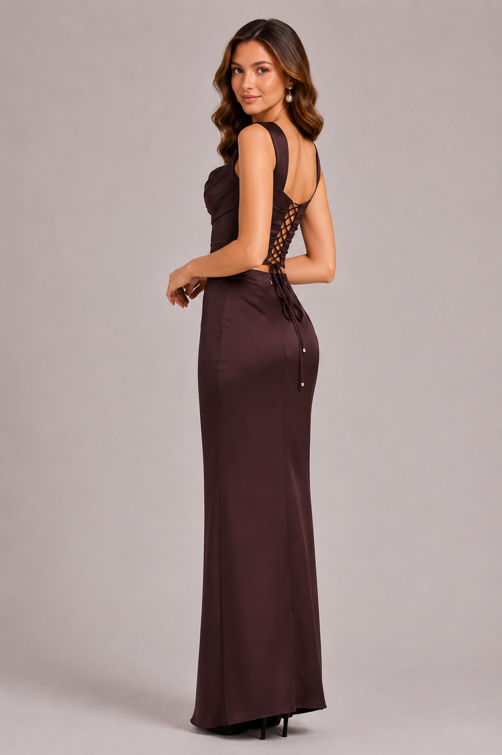 Woman wearing a burgundy evening gown with lace detailing on a plain background