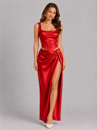 Woman wearing a red satin evening gown with a high slit on a gray background