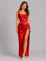 Woman wearing a red satin evening gown with a high slit on a gray background