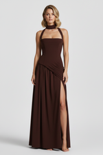 Woman wearing a brown evening gown with a slit on a white background
