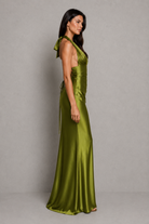 Woman wearing a green satin halter neck gown against a gray background