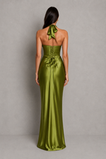 Woman wearing a green satin gown with a halter neck design on a gray background