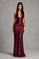 Woman wearing a burgundy satin gown against a gray background
