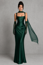 Woman wearing a green evening gown with a sheer overlay against a gray background