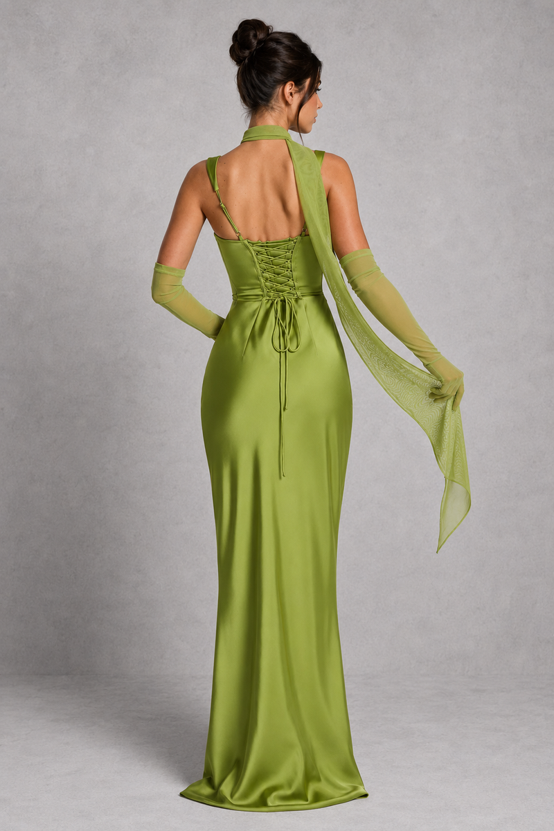 Woman wearing a green evening gown with a sheer overlay on a gray background