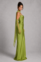 Woman wearing a green evening gown with a sheer overlay on a gray background