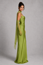 Woman wearing a green evening gown with a sheer overlay on a gray background