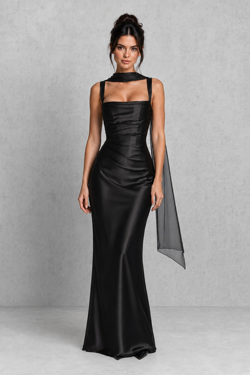 Woman wearing a black satin gown with a cape on a gray background