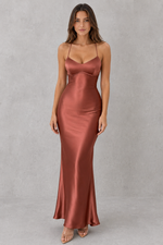 Woman wearing a satin slip dress against a gray background