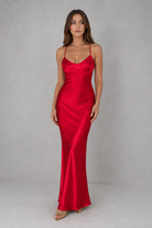Woman wearing a red satin dress against a gray background