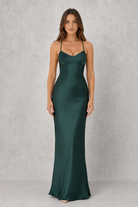 Woman wearing a green satin gown against a gray background