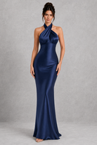 Woman wearing a blue satin gown against a gray background