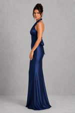 Woman wearing a navy blue evening gown against a gray background