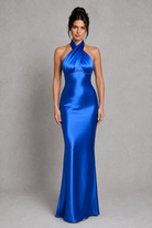 Woman wearing a blue satin evening gown against a gray background