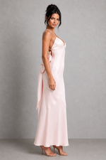 Woman wearing a pink satin dress against a gray background