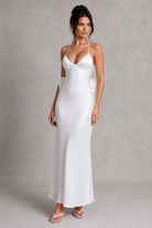 Woman wearing a white slip dress against a plain background
