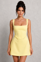 Woman wearing a yellow dress against a gray background