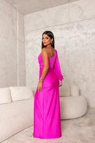 Woman in a bright pink dress standing in a minimalistic room with white walls and furniture.