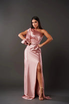 Woman wearing a pink satin one-shoulder dress with a slit on a gray background