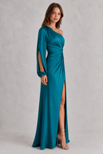 Woman wearing a teal one-shoulder evening gown with a slit on a gray background