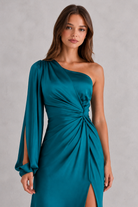Woman wearing a teal one-shoulder dress against a gray background