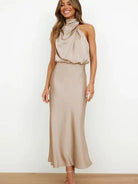 Woman wearing a beige halter neck dress against a white background