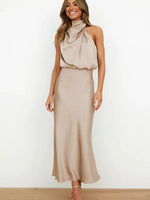 Woman wearing a beige halter neck dress against a white background