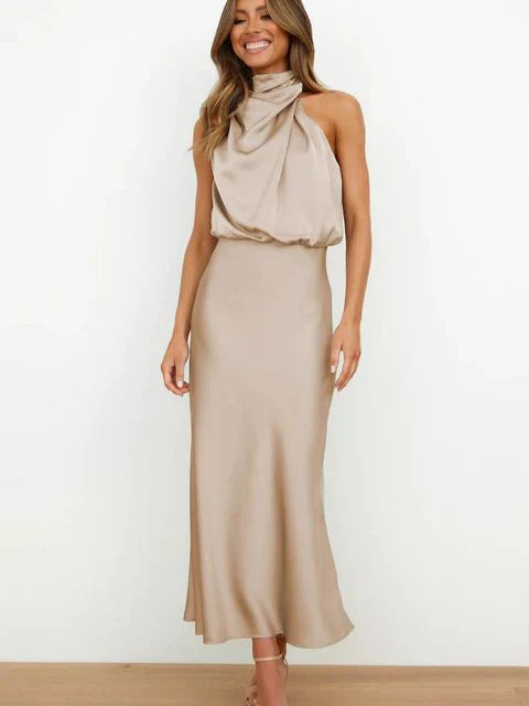 Woman wearing a beige halter neck dress against a white background